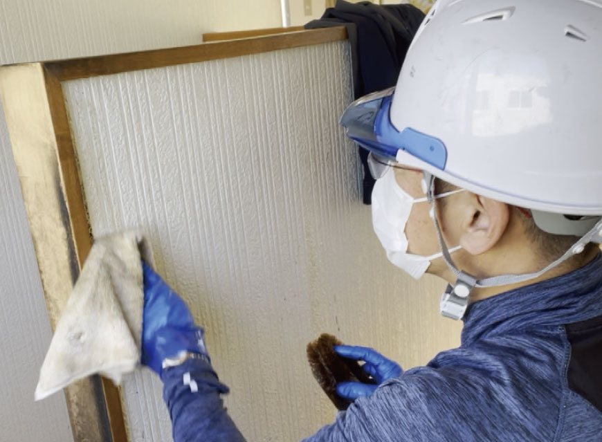 防護具を着けて壁面を清掃する作業員